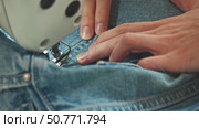 woman is working on jeans repair using industrial sewing machine. Hands carefully guide fabric under needle. Slow motion. Стоковое видео, видеограф Strunov David / Фотобанк Лори
