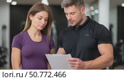 Personal trainer explaining training plan to young woman in gym. Стоковое AI-видео, аниматор Юрий Поздников / Фотобанк Лори