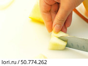 Chef's knife cutting a melon slice into small pieces for a child, showcasing safe food preparation. Стоковое фото, фотограф Татьяна Степанищева / Фотобанк Лори