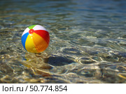 Colorful beach ball floating on water. Стоковое AI-изображение, AI-художник Boris Vasilenko / Фотобанк Лори