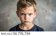 Portrait of an angry boy with furrowed brows expressing strong emotion and defiance, representing childhood moods, tantrums, or emotional expression. Стоковое AI-изображение, AI-художник Ольга Сухарева / Фотобанк Лори