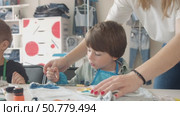 A young mother is engaged in creative work with her child, carefully decorating denim clothes together. Стоковое видео, видеограф Strunov David / Фотобанк Лори