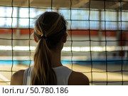 Young athlete watching padel court from behind netting. Стоковое AI-изображение, AI-художник Иван Рябоконь / Фотобанк Лори