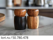 Two wooden salt and pepper grinders sitting on marble countertop. Стоковое AI-изображение, AI-художник Иван Рябоконь / Фотобанк Лори