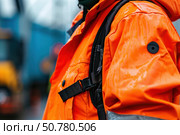 Dockworker wearing high visibility orange rain jacket and backpack. Стоковое AI-изображение, AI-художник Иван Рябоконь / Фотобанк Лори