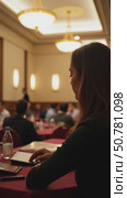 Woman Focused at a Conference in a Cozy Hall, Surrounded by Engaged Attendees. Concept of Event Planning and Public Speaking. Стоковое AI-видео, аниматор Sergey Grishin / Фотобанк Лори