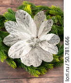 Elegant glittered poinsettia-style ornament with silver leaves on pine branches. Perfect for handmade Christmas decor and festive holiday atmosphere. Стоковое фото, фотограф Татьяна Терехина / Фотобанк Лори
