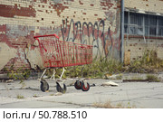 Red shopping cart abandoned in derelict urban area symbolizing consumerism and decay. Стоковое AI-изображение, AI-художник Иван Рябоконь / Фотобанк Лори