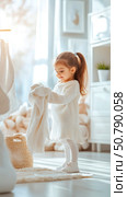 Adorable Toddler Girl Folding Laundry in Bright Room. Стоковое фото, фотограф Данила Большаков / Фотобанк Лори