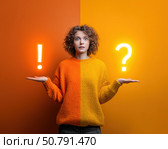 Молодая женщина стоит держа в одной руке вопросительный знак, а в другой — восклицательный, символизирующий принятие решения или неопределённость. Стоковое AI-изображение, AI-художник ArtVladZ / Фотобанк Лори