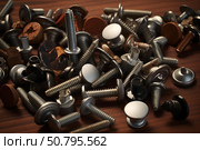 Different screws and fasteners lying on wooden table top. Стоковое AI-изображение, AI-художник Иван Рябоконь / Фотобанк Лори