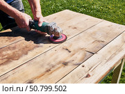 Grinding wood tabletop with handheld angle grinder, sanding disc removing material from surface in detailed view of tool in action. Стоковое фото, фотограф Владимир Григорьев / Фотобанк Лори
