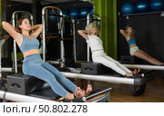 Young woman sitting on box set equipment reformer performs for abdominal muscles. Стоковое фото, фотограф Яков Филимонов / Фотобанк Лори