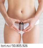 Unrecognizable woman in white panties holds a mini grater. Metaphor of the bristles after depilation in the bikini area of the girl. Spiky hair is an argument for epilation. Стоковое фото, фотограф Михаил Решетников / Фотобанк Лори
