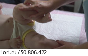 Slow-motion video of an infant under one year receiving a leg massage to enhance left hip joint mobility. Pediatric physiotherapy session. Стоковое видео, видеограф Татьяна Степанищева / Фотобанк Лори