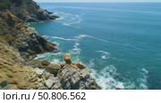 Rocky coastline with ocean waves under clear blue sky. Стоковое AI-видео, аниматор Андрей Бажанов / Фотобанк Лори