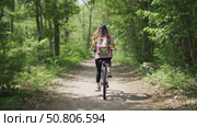 Young woman biking along a dirt path in a green forest. Стоковое AI-видео, аниматор Андрей Бажанов / Фотобанк Лори