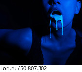 A thick white liquid flows down the lips of a young European girl. Dripping down. Ultraviolet, blue light. Close-up portrait. Spit out. Стоковое фото, фотограф Михаил Решетников / Фотобанк Лори