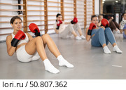 Young girl doing abdominal exercise with boxing gloves in group. Стоковое фото, фотограф Яков Филимонов / Фотобанк Лори