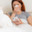 A woman suffering from an attack of an allergy blows her nose in her nose raft. White cat in the foreground. Girl with a cold in bed at home. Стоковое фото, фотограф Михаил Решетников / Фотобанк Лори