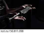 Close-up Black leather lash in female hands. Monochrome cropped photo of bdsms toys. A woman stands in the dark and holds a whip in her palms. Стоковое фото, фотограф Михаил Решетников / Фотобанк Лори