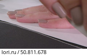 Hand of woman with delicate beige manicure carefully tracing pattern template on fabric with chalk, concept of preparation process for sewing clothes in garment factory. Стоковое видео, видеограф Дмитрий Нечаев / Фотобанк Лори