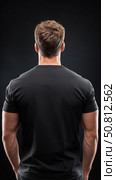 Muscular man standing confidently against dark background in studio setting. Стоковое AI-изображение, AI-художник Katsiaryna Repich / Фотобанк Лори