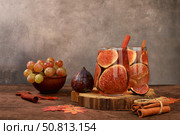 Cocktail with figs, cinnamon, grapes on a dark background with autumn leaves, a warming vitamin drink during the flu and cold season, alcoholic and non-alcoholic grog, cider, lemonade. Detox diet concept, selective focus. Стоковое фото, фотограф Светлана Балынь / Фотобанк Лори