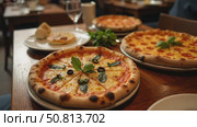 Authentic gourmet pizza selection served on restaurant table for sharing between friends during night out. Fresh ingridients and crispy crust on italian traditional plate. Стоковое AI-видео, аниматор Sergey Grishin / Фотобанк Лори