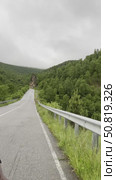 The car drives along a narrow road surrounded by mountains, vibrant greenery and misty hills. The atmosphere is peaceful, nature envelops the road, inviting you to explore. Редакционное видео, видеограф Зворыгина Елена / Фотобанк Лори