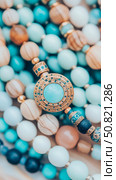 Bohemian Beadwork: A turquoise stone pendant with golden embellishments on strands of beads. Стоковое AI-изображение, AI-художник Данила Большаков / Фотобанк Лори
