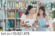Mother and teenage daughter shopping for makeup in beauty section of supermarket, smiling while comparing different decorative cosmetics products. Стоковое видео, видеограф Яков Филимонов / Фотобанк Лори