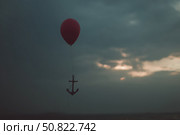 Red balloon with an anchor drifting against a moody sky at dusk near the water. Стоковое AI-изображение, AI-художник Сергей Толмачёв / Фотобанк Лори