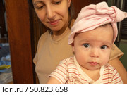 Молодая мама держит пятимесячную девочку на руках в старинном деревянном коридоре. Стоковое фото, фотограф Владислав Войтов / Фотобанк Лори