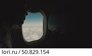 Hand in closes airplane window shade, blocking view of blue sky and clouds, inside aircraft cabin, passenger seatback and porthole, realistic travel scene showing end of journey or landing preparation. Стоковое видео, видеограф Сергей Тимофеев / Фотобанк Лори