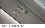 Airplane passenger adjusting overhead air vent nozzle, close up of aircraft cabin control panel with ventilation, call buttons, seat belt and no smoking signs, passenger hand, concept travel. Стоковое видео, видеограф Сергей Тимофеев / Фотобанк Лори