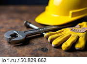 On the table is a monkey wrench, rubber gloves and a yellow helmet. Стоковое AI-изображение, AI-художник Галина Эмберг / Фотобанк Лори