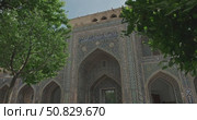 Colorful facade of Islamic madrasa with intricate geometric mosaics and traditional oriental architecture in Samarkand Uzbekistan under blue sky, arched entrance, tile ornament with Arabic calligraphy. Стоковое видео, видеограф Сергей Тимофеев / Фотобанк Лори