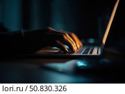 Person typing at laptop computer at night. Female uses keyboard, shakes buttons with fingers. Internet security, cyber attack. Trendy neon light. Creative dark color of orange, black, and teal blue. Стоковое AI-изображение, AI-художник Марина Демидюк / Фотобанк Лори