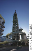 Modern architectural structure featuring a tall observation tower with a spiral ramp, surrounded by contemporary buildings under a clear blue sky, showcasing innovative design and urban landscape. Стоковое видео, видеограф Данил Руденко / Фотобанк Лори