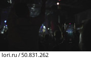 Person holding smartphone in a dark concert venue, capturing vibrant stage lights and crowd energy, showcasing the excitement of live music events and audience engagement. Стоковое видео, видеограф Данил Руденко / Фотобанк Лори