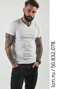 Attractive brutal tattooed bearded guy poses in black jeans and blank white t-shirt from premium thin summer cotton, isolated on white mockup. Стоковое AI-видео, аниматор Sergey Grishin / Фотобанк Лори