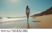 Camera follows woman walk barefoot on beautiful calm sandy beach at resort or hotel. Ocean waves surf roll over her feet. Concept tranquility and self care in peaceful setting. Стоковое AI-видео, аниматор Sergey Grishin / Фотобанк Лори