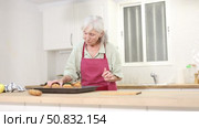 Smiling senior woman putting hot just prepared cupcakes on kitchen table. Стоковое видео, видеограф Яков Филимонов / Фотобанк Лори
