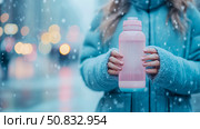 Winter hydration: Woman holding a water bottle on a snowy day, promoting healthy lifestyle and cold weather wellness. Стоковое AI-изображение, AI-художник Данила Большаков / Фотобанк Лори
