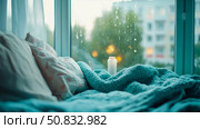 Cozy Rainy Day: Relaxation Nook with Soft Bedding by Window, Comfort and Serenity. Стоковое AI-изображение, AI-художник Данила Большаков / Фотобанк Лори