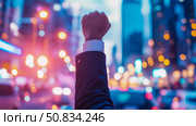 Empowerment: A Fist Raised in Defiance Against a Vibrant City at Dusk. Стоковое AI-изображение, AI-художник Данила Большаков / Фотобанк Лори