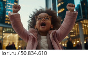 Concept: Childhood Joyful victory celebration in urban setting with little girl in pink coat expressing glee. Стоковое AI-изображение, AI-художник Данила Большаков / Фотобанк Лори