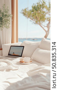 Relaxing Seaside Escape: A cozy nook with laptop and drinks overlooking tranquil ocean, ideal for leisure or remote work, print, card, poster. Стоковое AI-изображение, AI-художник Данила Большаков / Фотобанк Лори