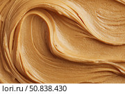 Creamy peanut butter spread swirl surface. Closeup, full frame. Crunchy Peanut butter background. American cuisine traditional product. Appetizing textured smears. Food paste from ground roasted nuts. Стоковое AI-изображение, AI-художник Марина Демидюк / Фотобанк Лори